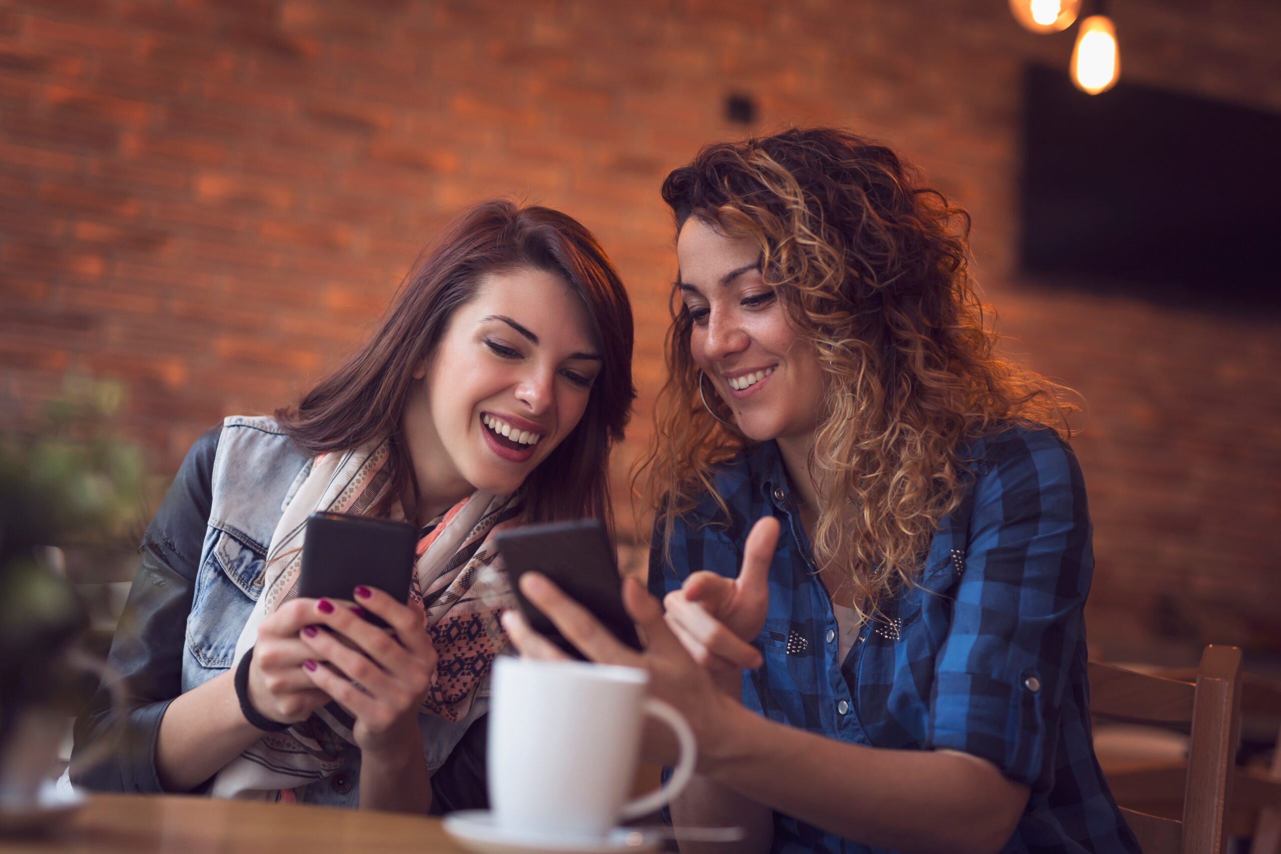 Duas garotas bebendo café e compartilhando nas redes sociais